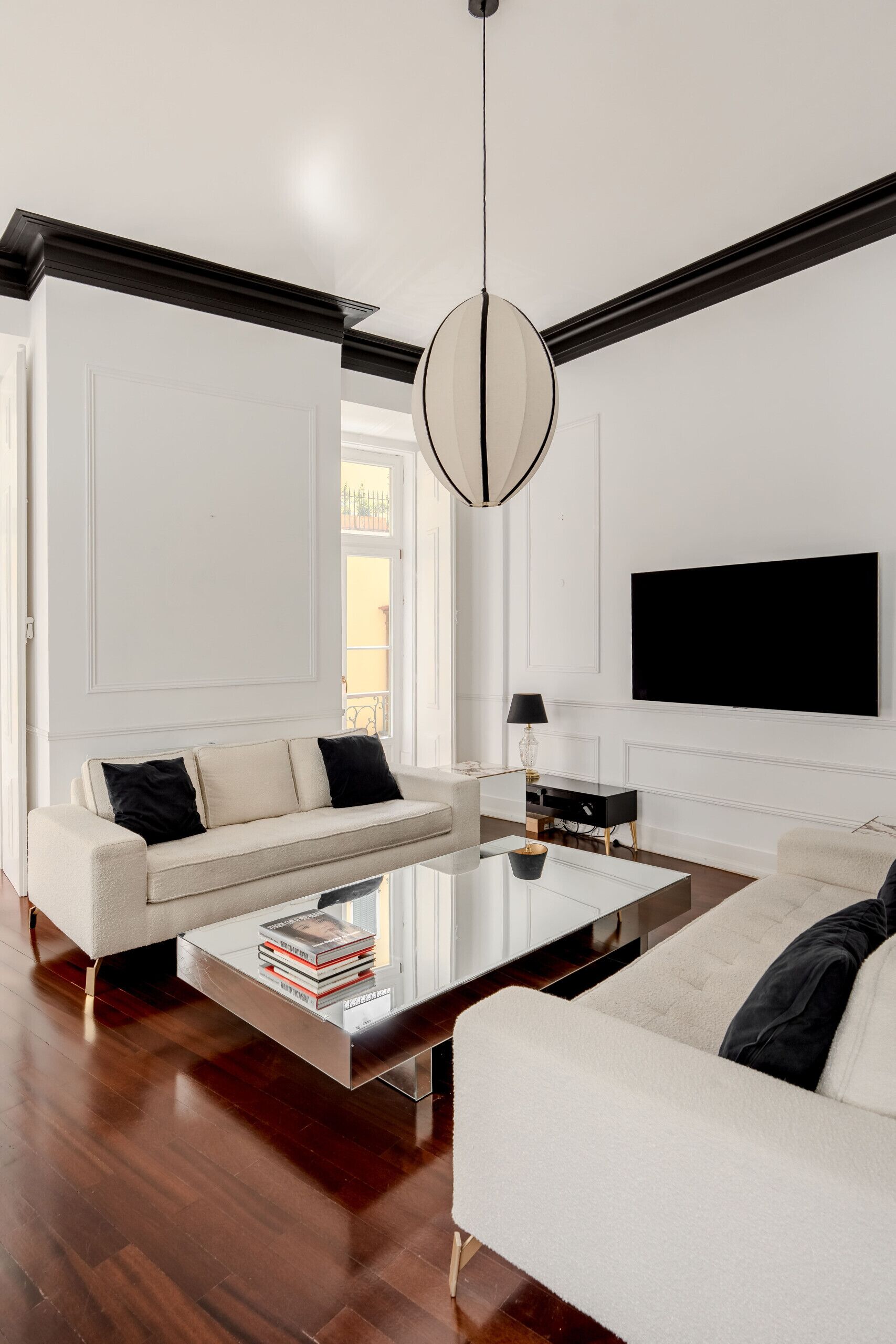Una sala moderna con sofá, mesa de centro, televisor y una lámpara colgante.