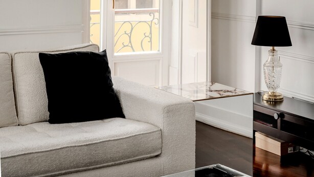A room with a sofa, a lamp, a window, and a door. - Chiado Deluxe by Homing (Lisbon)