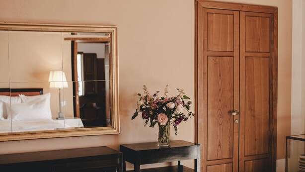 A hotel room with a bed, a bedside table with a vase of flowers, a large mirror, and a wooden wardrobe. - Ma' Ca' - Cupola d' oro (Praiano)