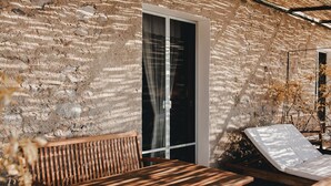 A stone wall exterior, a wooden bench, a table, and a sun lounger. - Ma' Ca' - Red Room (Praiano)