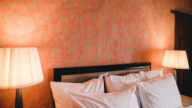 A hotel room with a bed, two bedside lamps, and a floral wallpaper pattern. - Ma' Ca' - Red Room (Praiano)