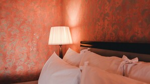 A neatly made bed with white linens and pillows, a bedside lamp, and a patterned wall in a hotel room. - Ma' Ca' - Red Room (Praiano)