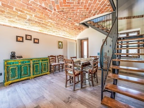 A dining area with a brick ceiling, wooden chairs, a green cabinet, and a staircase. - Casa Vescovo by Interhome (Asti)