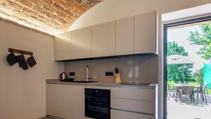 Cozinha moderna com teto de tijolos, forno embutido e vista para um pátio externo.