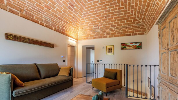 Uma sala de estar com teto de tijolos, um sofá, uma mesa de centro e um quadro na parede.