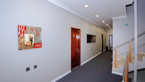 A hallway with a wooden door, a wall-mounted artwork, and a staircase with a handrail. - Kichik Gala 98 (Baku)
