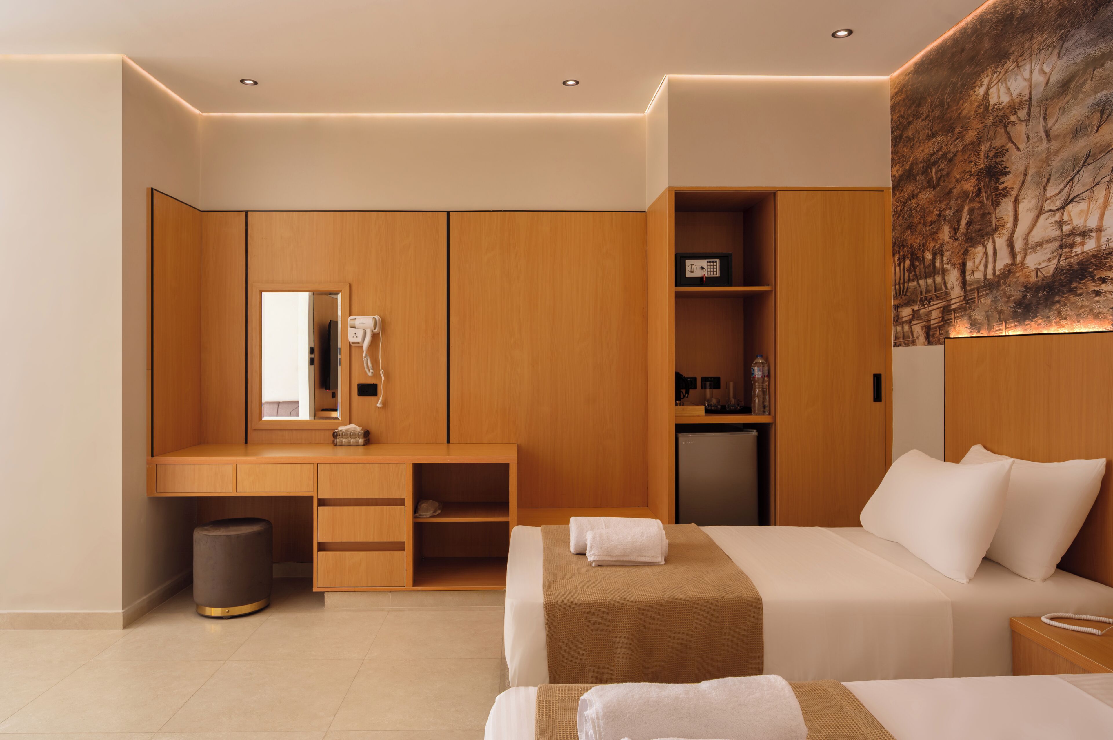 A modern hotel room with a wooden desk, a bed, a small table, and a wall-mounted TV.