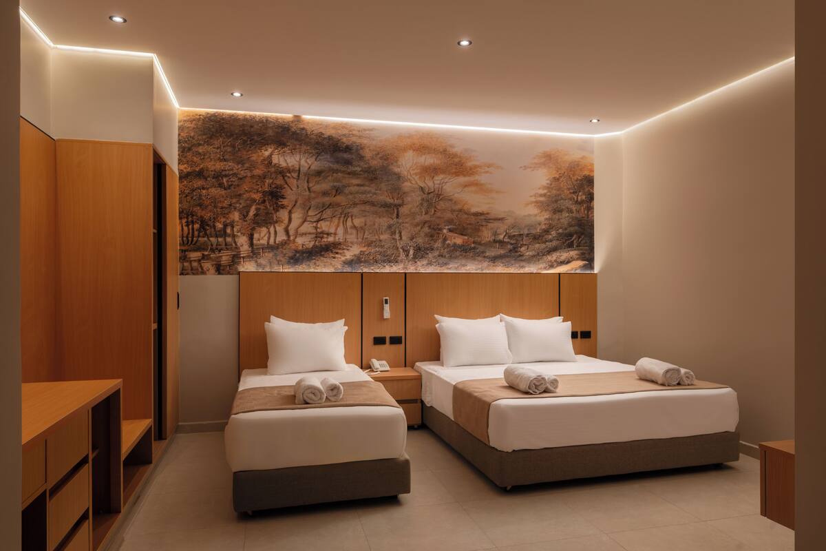 A modern hotel room with two beds, a large painting on the wall, wooden furniture, and a small desk.