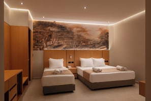 Una habitación de hotel moderna con dos camas, un cuadro grande en la pared, muebles de madera y un escritorio pequeño.