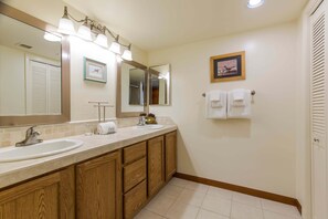 Une salle de bain équipée d’un lavabo, d’un miroir, d’une commode, d’un porte-serviettes et d’un tableau encadré.