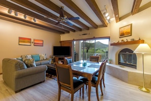 A living room with a sofa, TV, dining table, chairs, and a fireplace.