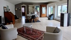 Amplia sala de estar con una mesa de comedor y sillas, un sofá y un ventanal que proporciona luz natural.