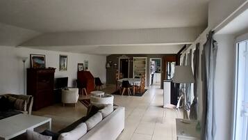 A spacious living room with a large sofa, a dining area, and a kitchen in the background.