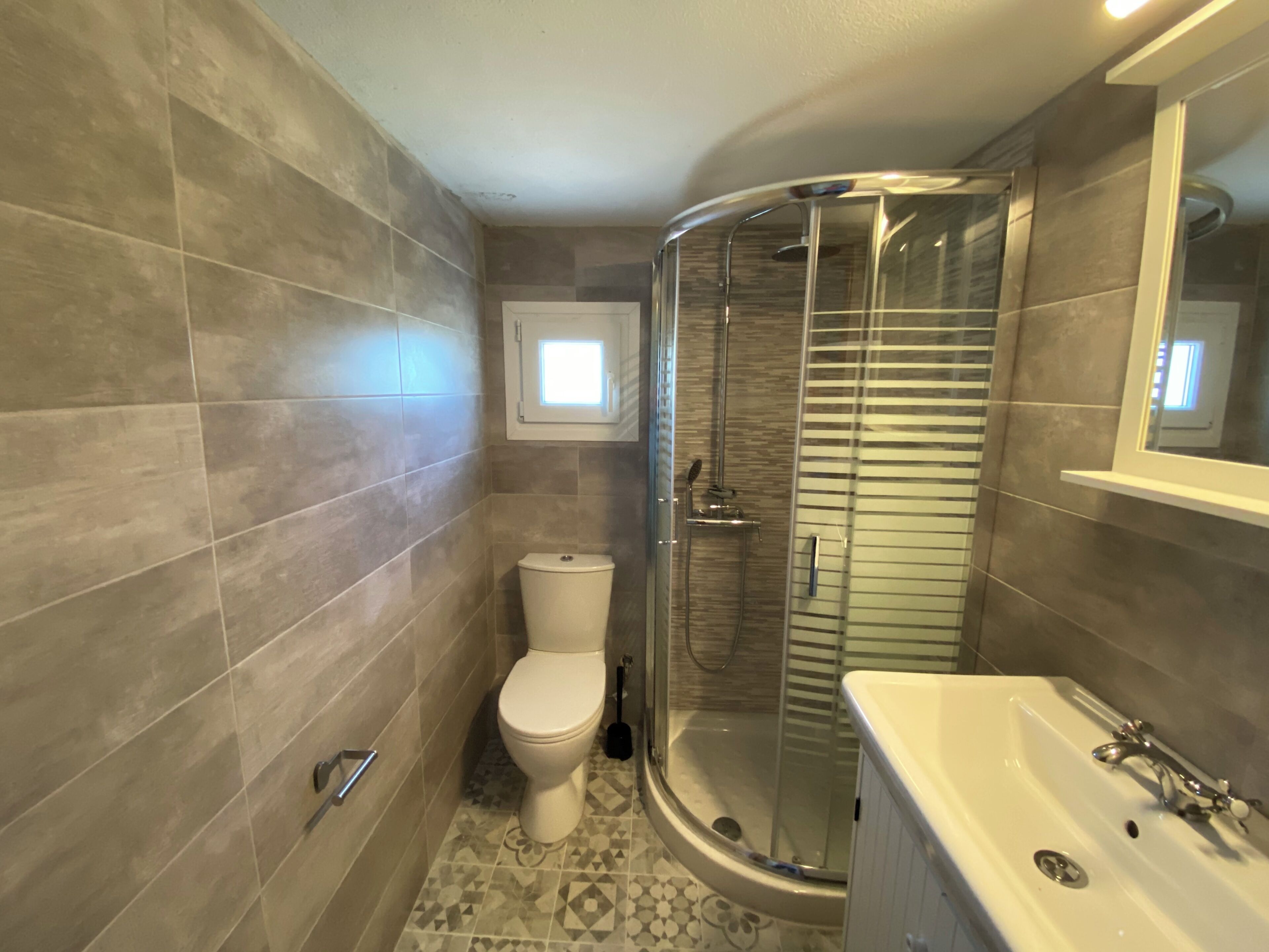 A bathroom with a glass-enclosed shower, a toilet, and a bathtub.