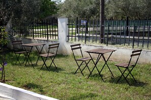 Outdoor seating with tables and chairs, a concrete wall, and a metal fence. - Villa- Nea Kalikrateia - 2-bdroom Apartment (Nea Propontida)