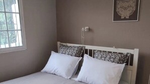 A bedroom with a bed, pillows, a bedside table, a wall-mounted light, and a window. - Villa- Nea Kalikrateia - 2-bdroom Apartment (Nea Propontida)