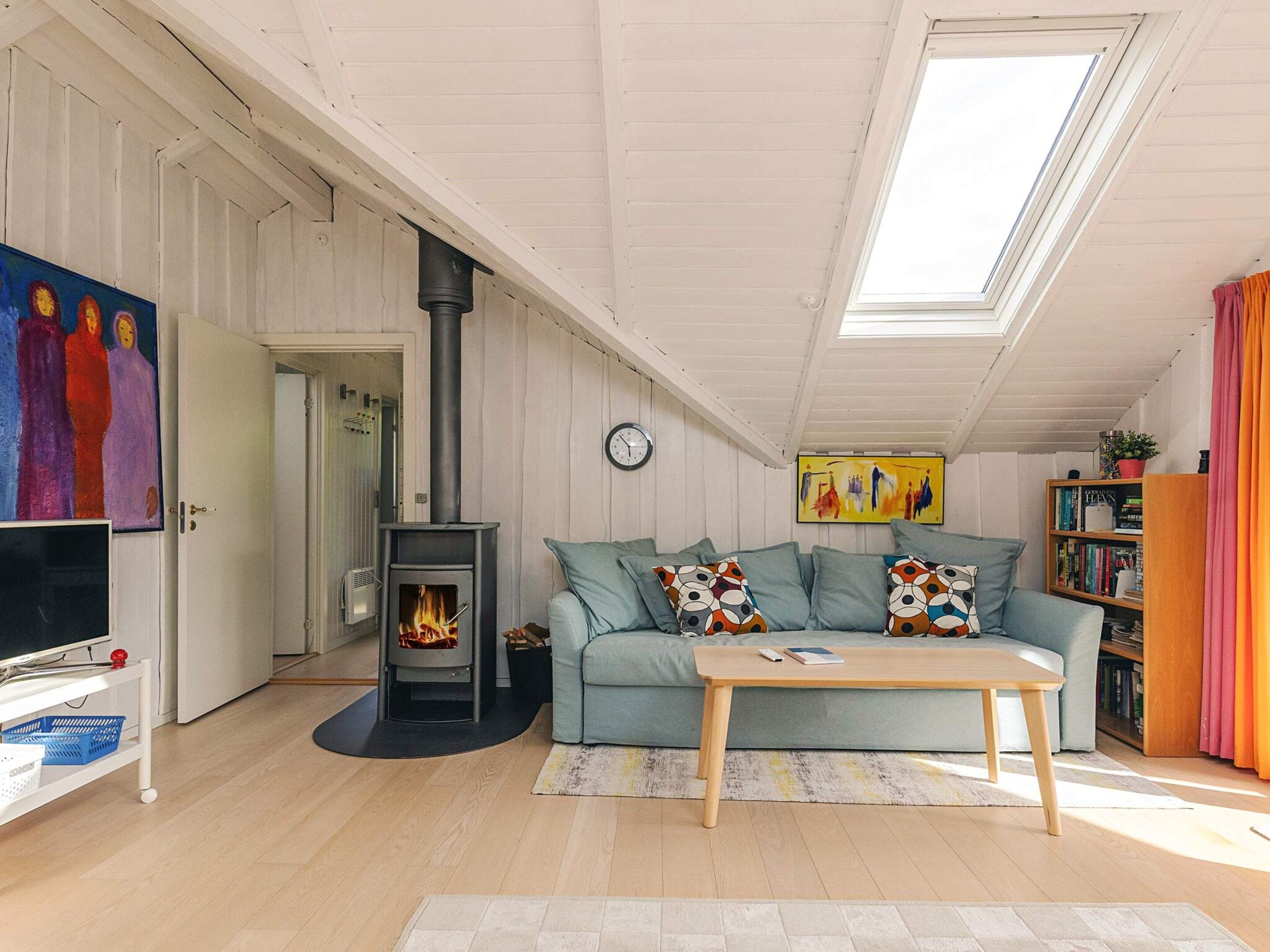 A cozy living room with a fireplace, a sofa, a coffee table, and a bookshelf.