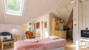 Una habitación con cama, escritorio, silla, televisor y un área de cocina.