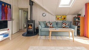 Una sala acogedora con chimenea, un sofá, una mesita de centro y una estantería.