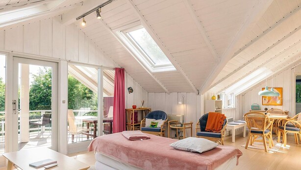 Amplio dormitorio tipo loft con una cama grande, una zona de comedor y un balcón con mobiliario de exterior.