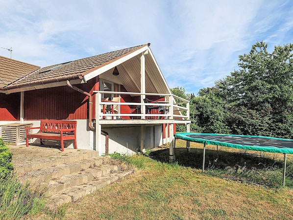 A red building with a balcony, a trampoline, and a bench. - 8 Person Holiday Home in Bogo By (Bogø By)