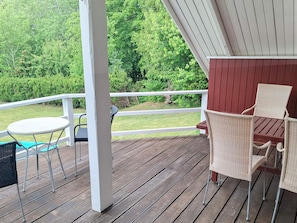 A wooden deck with a white railing, a small round table, and two wicker chairs. - 8 Person Holiday Home in Bogo By (Bogø By)
