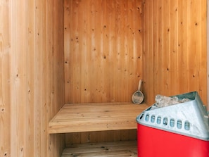 A sauna with a wooden interior, a bench, a metal ladle, and a red trash bin. - 8 Person Holiday Home in Bogo By (Bogø By)
