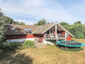 A red and white house with a balcony, a trampoline, and a garden. - 8 Person Holiday Home in Bogo By (Bogø By)