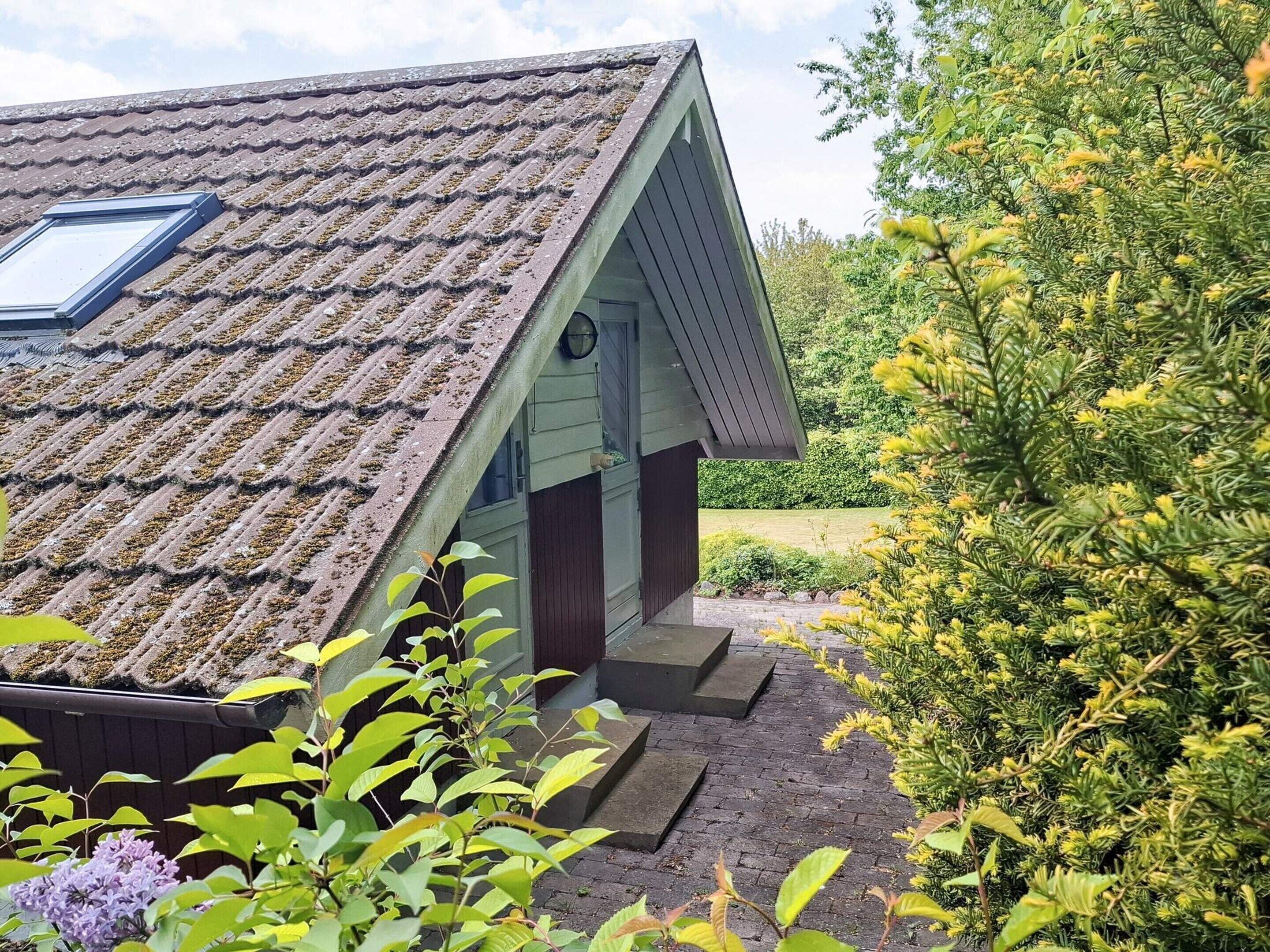 Ein Haus mit geneigtem Dach, einem Oberlicht und einer kleinen Veranda.