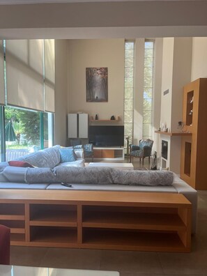 Una sala de estar moderna con un sofá, televisión y estanterías de madera.
