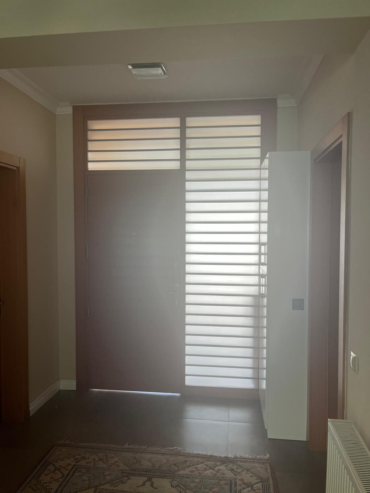 Ein Zimmer mit einer großen Schiebetür, einem Heizkörper und einem gemusterten Teppich.