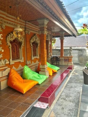 A covered outdoor seating area with colorful cushions, a tiled floor, and traditional architectural elements.