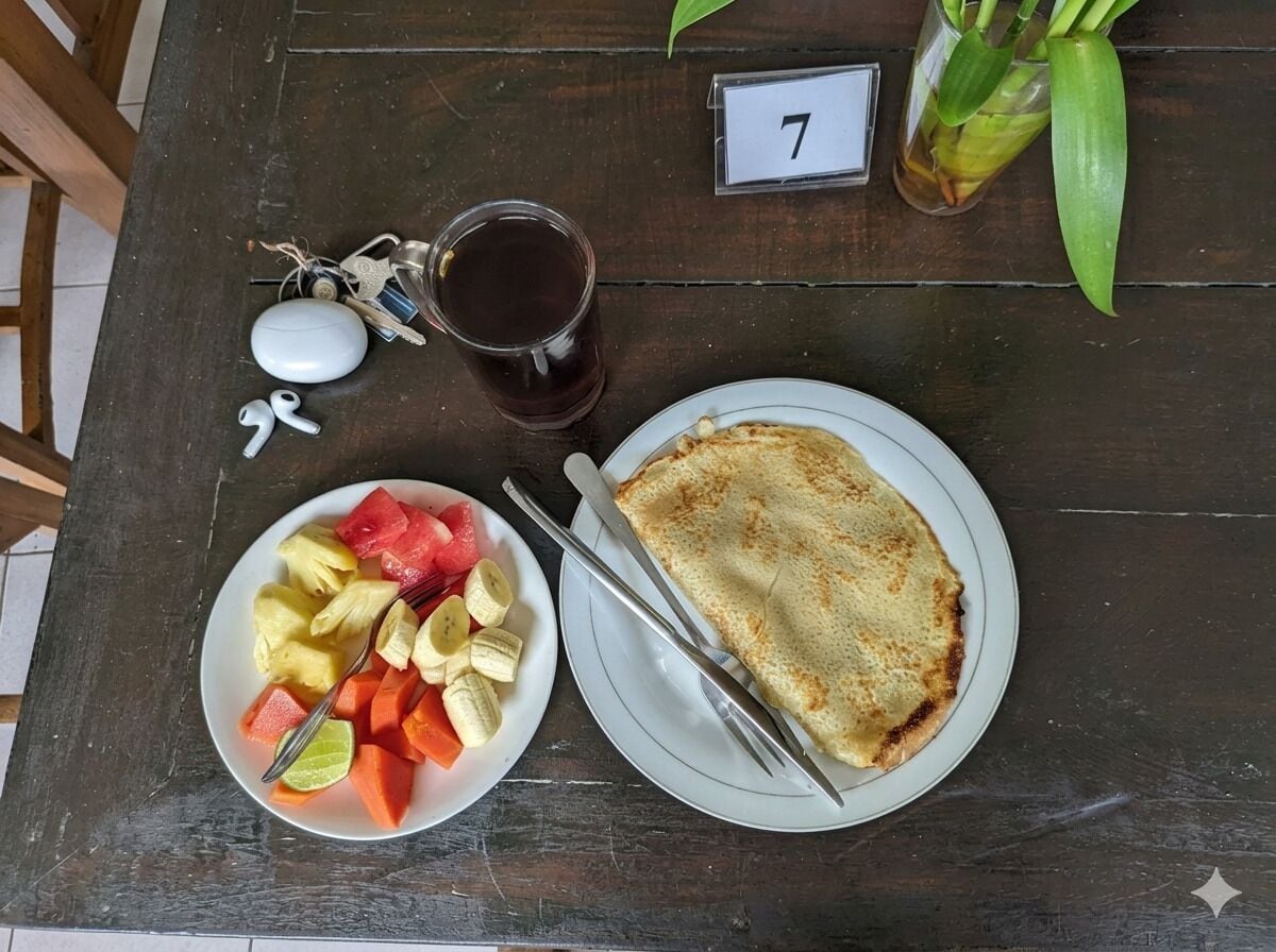 Una mesa de madera con un plato de comida, un vaso de líquido oscuro, llaves y un pequeño cartel con el número.