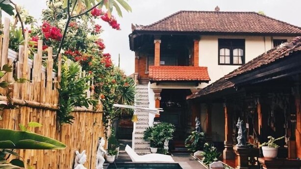 Un patio con piscina, cerca de bambú y una casa con techo de tejas.