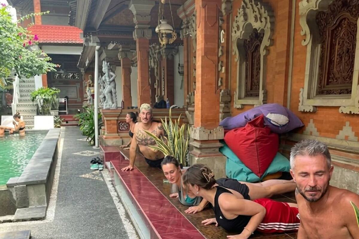 A group of people doing push-ups on a tiled ledge outside a building with ornate architecture.