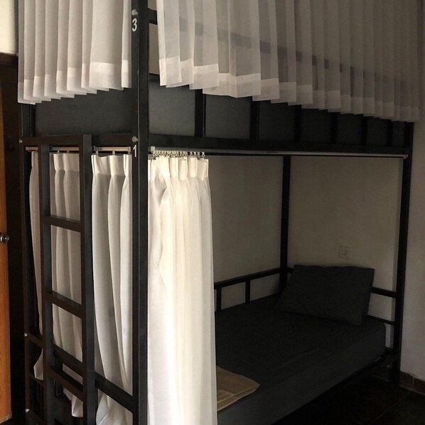 A bunk bed with white curtains and a wooden frame.