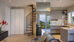 Une cuisine moderne dotée d’un îlot central intégré, d’un escalier menant à un balcon et d’un coin salon offrant une vue agréable.