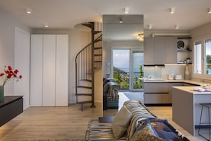 Eine moderne Küche mit integrierter Kücheninsel, einer Treppe zu einem Balkon und einer Sitzecke mit Aussicht.