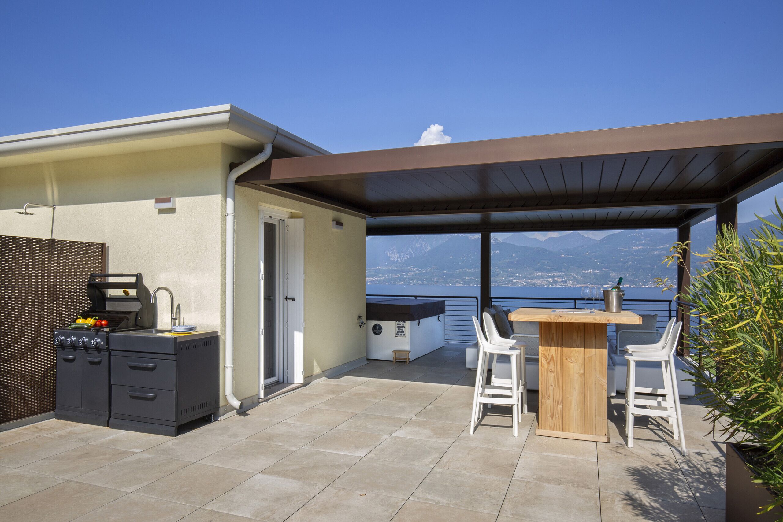 Un patio exterior con una parrilla, zona de bar y asientos.