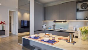 Une cuisine moderne dotée d’un îlot central, d’appareils électroménagers intégrés et d’une grande horloge murale.