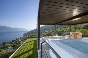 Ein moderner Poolbereich im Freien mit Blick auf einen See und Berge.