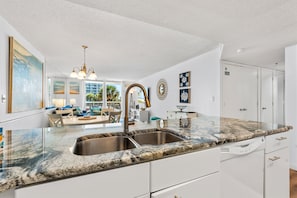 A modern kitchen with granite countertops, stainless steel sink, and white cabinetry. - South Hampton 107 Oceanview w/Pool & Beach (Myrtle Beach)