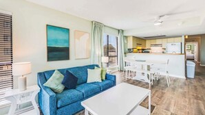 A living room with a sofa, a coffee table, and a dining area with a table and chairs.