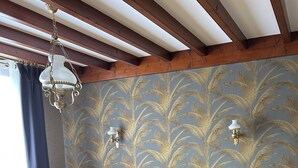 A bedroom with a bed, wooden floor, and a patterned wallpaper. - Les figuiers Charming stone house Pets welcome (Gonneville-Le Theil)