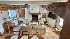 A living room with a sofa, chairs, a coffee table, a fireplace, and a television. - Les figuiers Charming stone house Pets welcome (Gonneville-Le Theil)