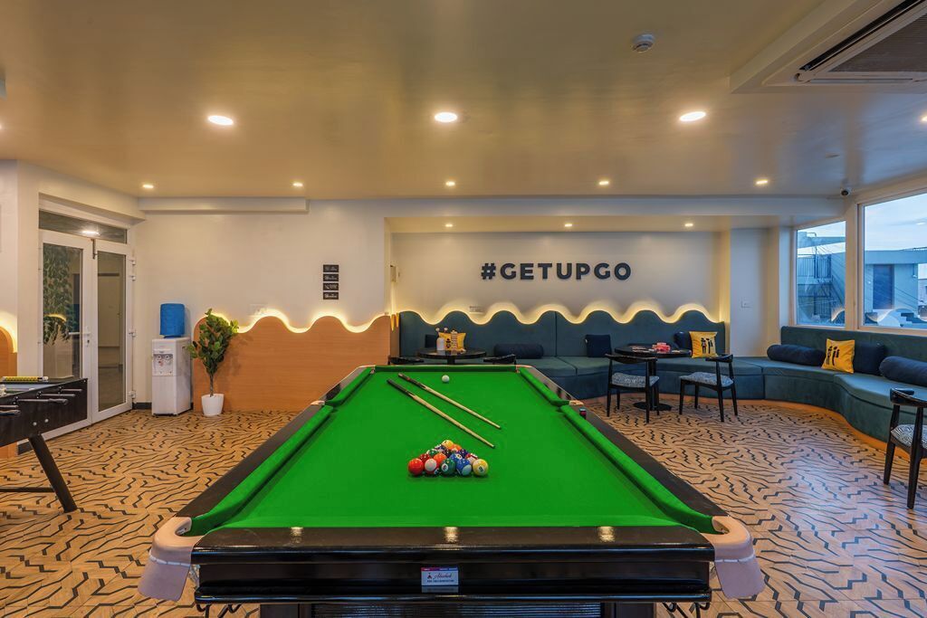 A pool table with cue sticks and balls, a sofa, and a wall with a hashtag sign.