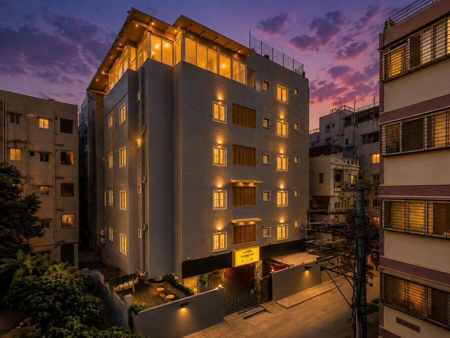 Un hotel de varios pisos con diseño moderno, que cuenta con un patio central y varios balcones.