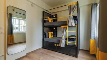 A bunk bed room with a mirror, a window, and a curtain.