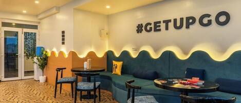 Ein moderner Lounge-Bereich mit einer gebogenen Couch, runden Tischen und einem gemusterten Boden.
