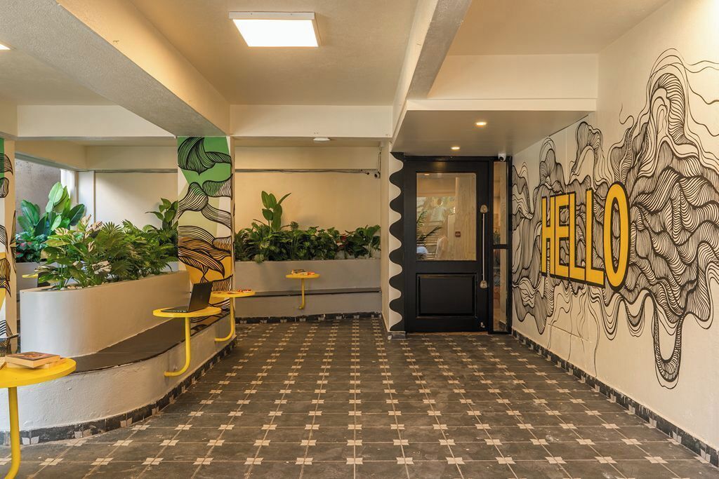 A hallway with a tiled floor, a reception desk, and a wall with a 'HELLO' mural.